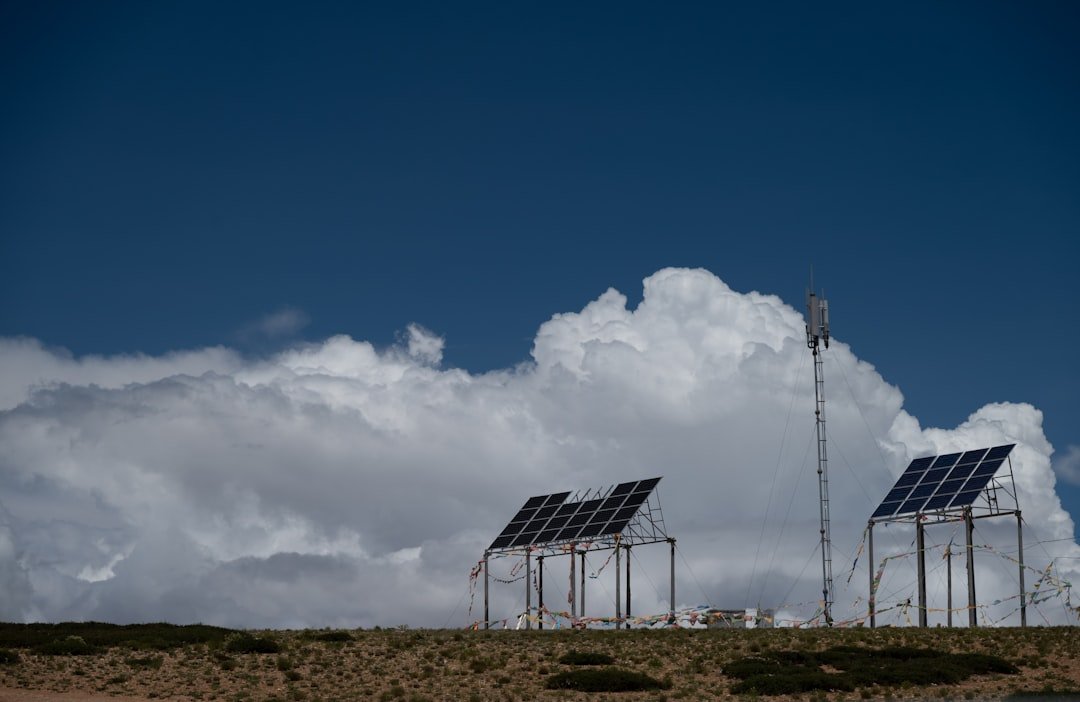 Solar panels and communication tower under a cloudy sky.