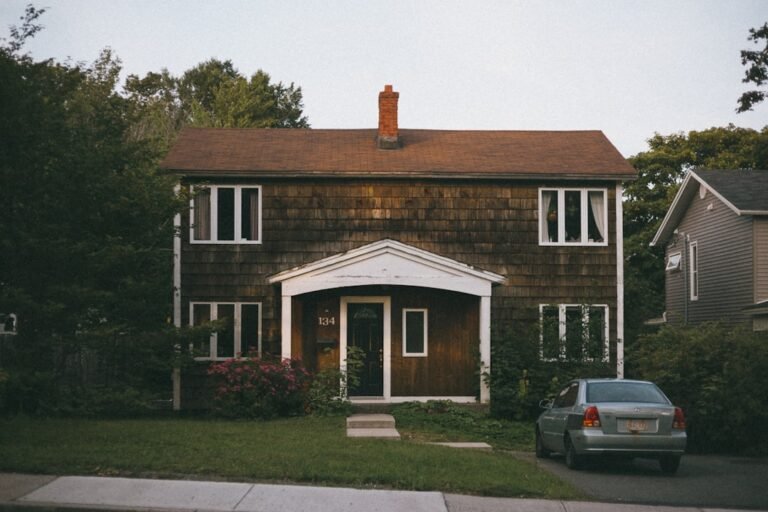 Black car parked in front of brown and white house