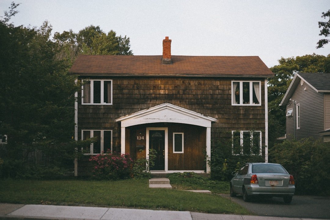 Black car parked in front of brown and white house