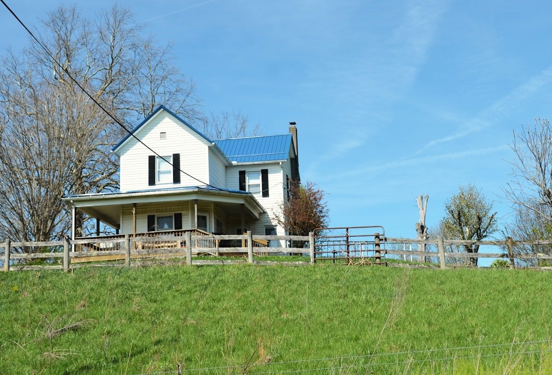 White farmhouse with blue roof and porch.