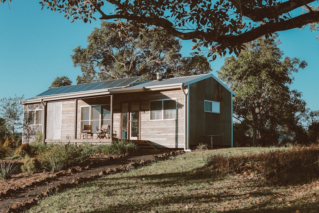 White wooden house near green trees under blue sky during daytime