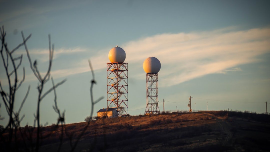 Two radar domes on towers on a hill.