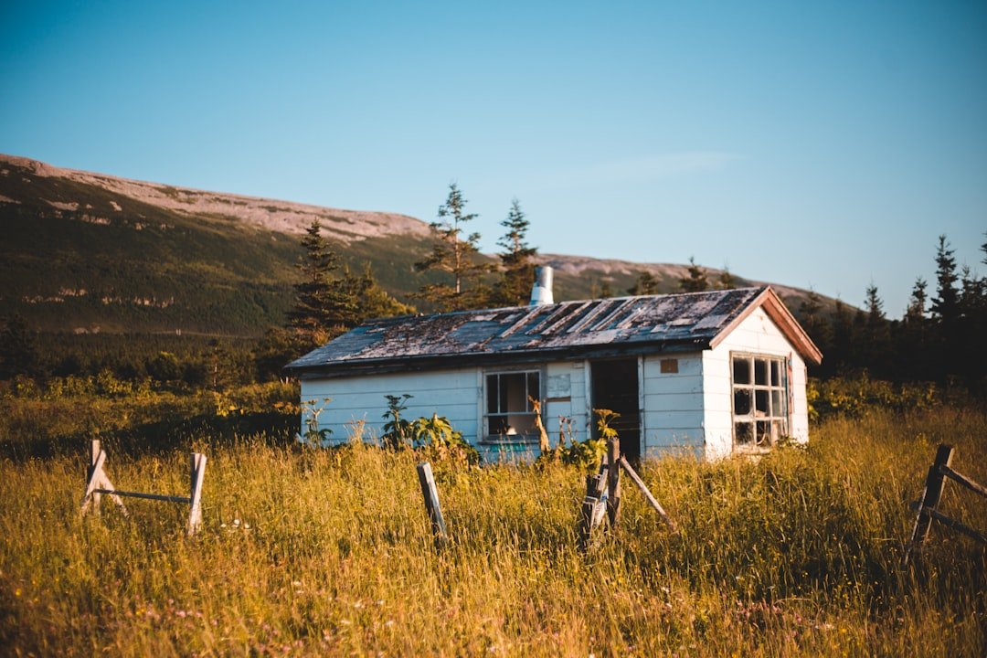White and brown wooden house near brown mountain under blue sky during daytime