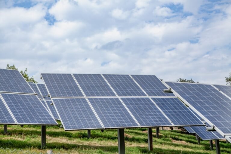 Solar panels in a field under a cloudy sky