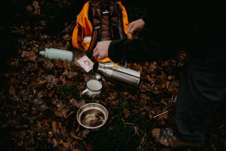 A person pouring water into a cup on the ground