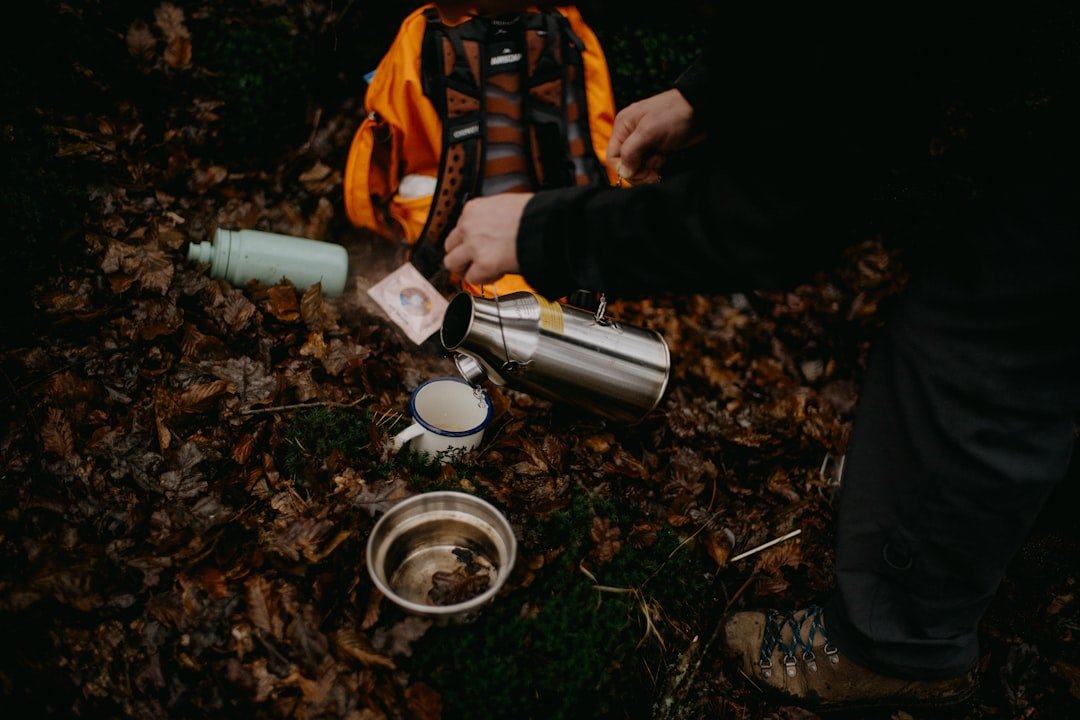 A person pouring water into a cup on the ground