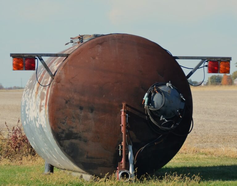 Rusty water tank with red lights in a field