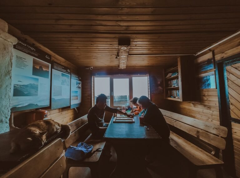 People sitting at a wooden table inside a rustic cabin.