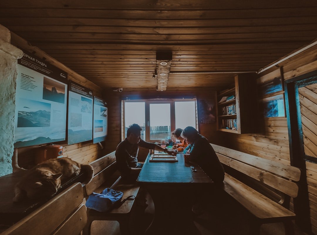 People sitting at a wooden table inside a rustic cabin.