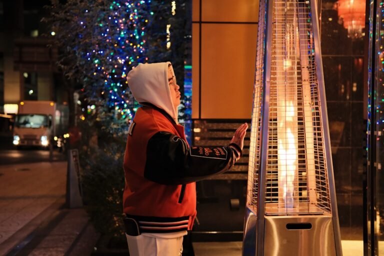 Person warming hands by outdoor patio heater at night