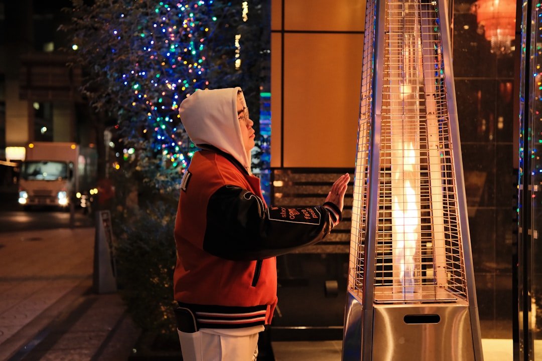 Person warming hands by outdoor patio heater at night