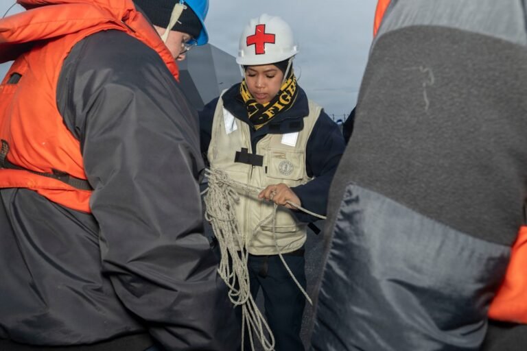 People in life jackets and hard hats holding rope