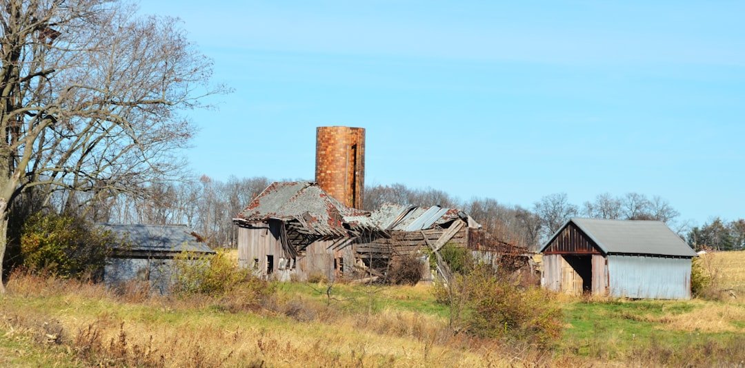 Dilapidated barn and silo under a clear blue sky