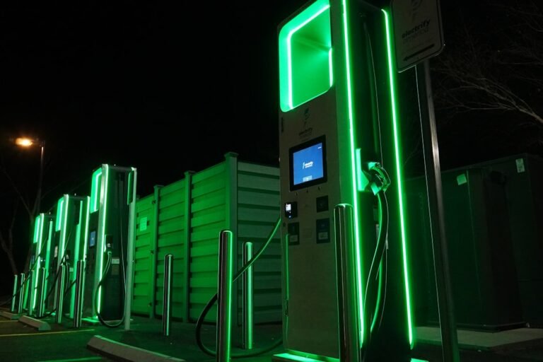 A row of green gas pumps at night