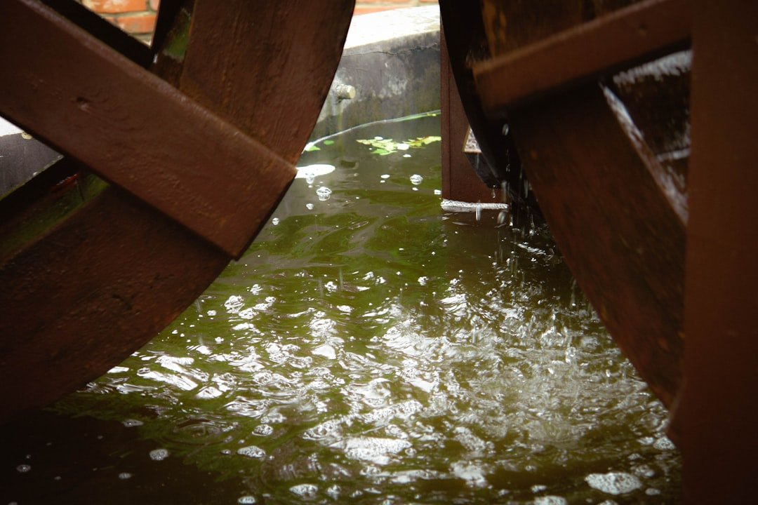 Wooden water wheels turning in murky green water