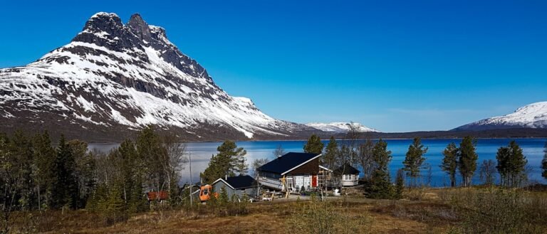 White and brown house near snow covered mountain during daytime