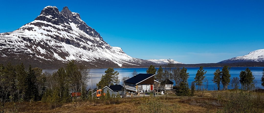 White and brown house near snow covered mountain during daytime